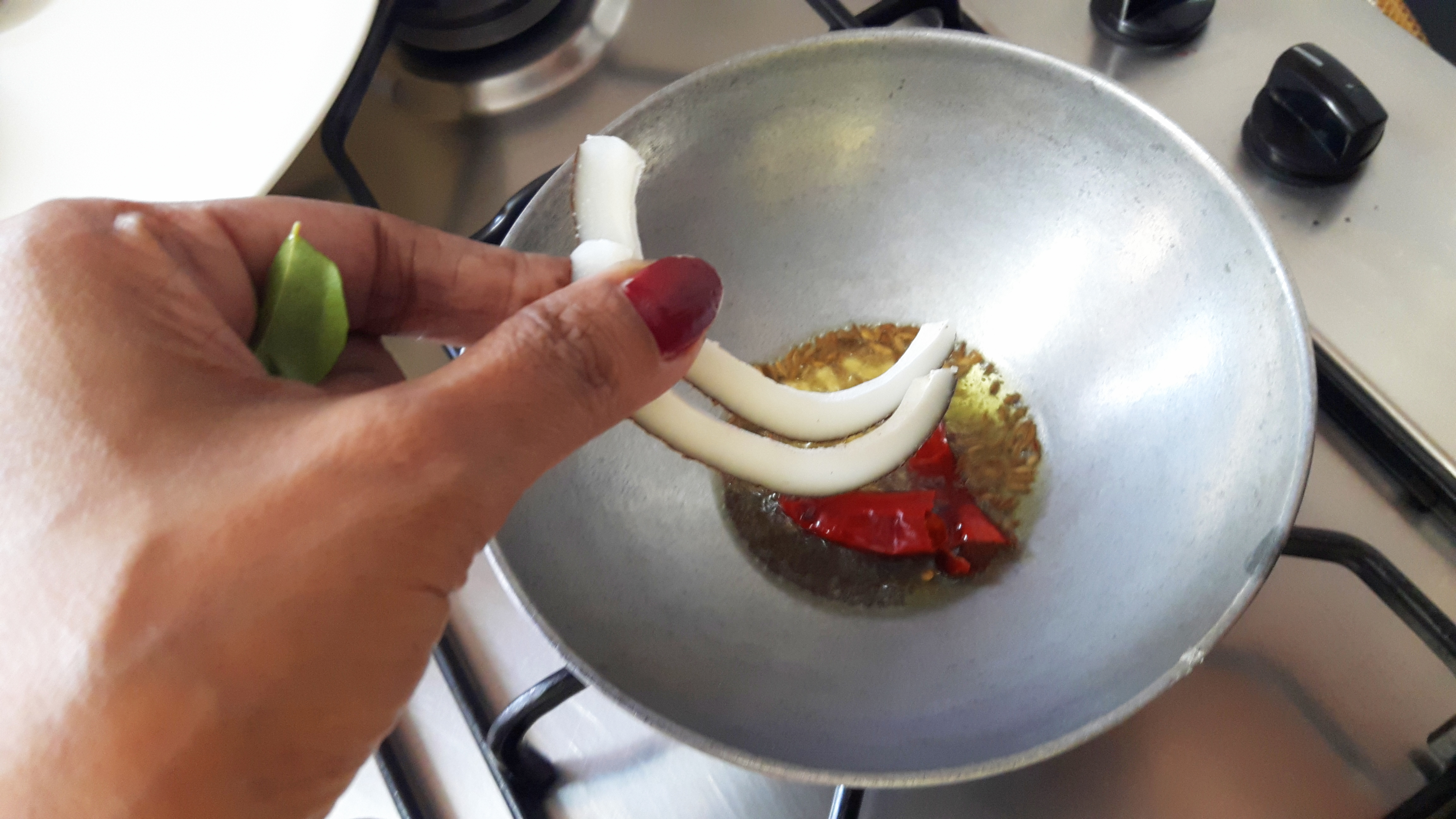 add mustard seed, whole red chili, split black gram cumin and sliced coconut