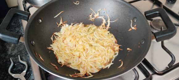 Add longitudinally chopped onion; fry it at high flame
