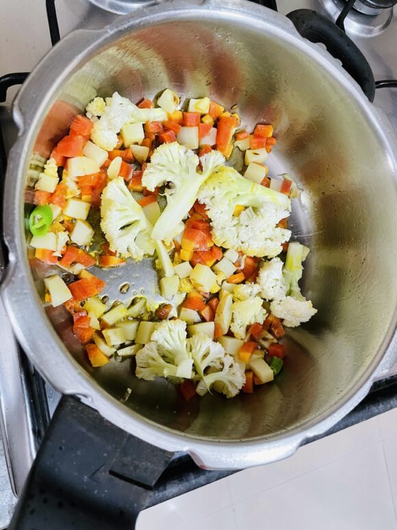 Heat ghee in a pressure cooker; add cumin, sputter for few seconds. Add chopped onion, ginger, garlic, green chilli