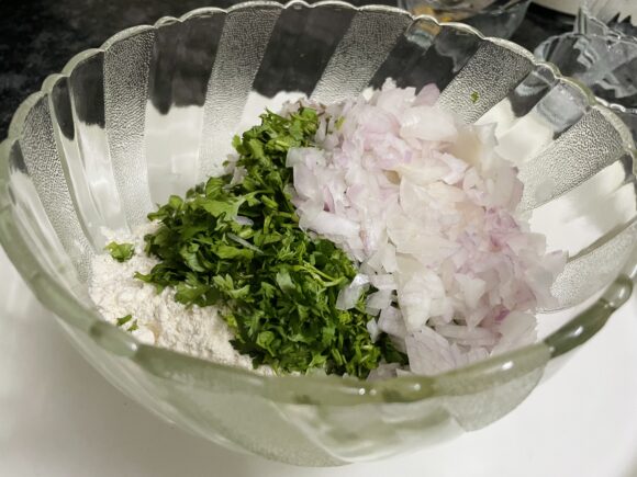 Take a wide vessel, put all flours along with salt, cumin, ajwain, turmeric powder, chopped and grind ingredients